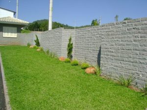 muro construido com pedra basalto na cidade de parai, conta com uma grama verde e arvores.